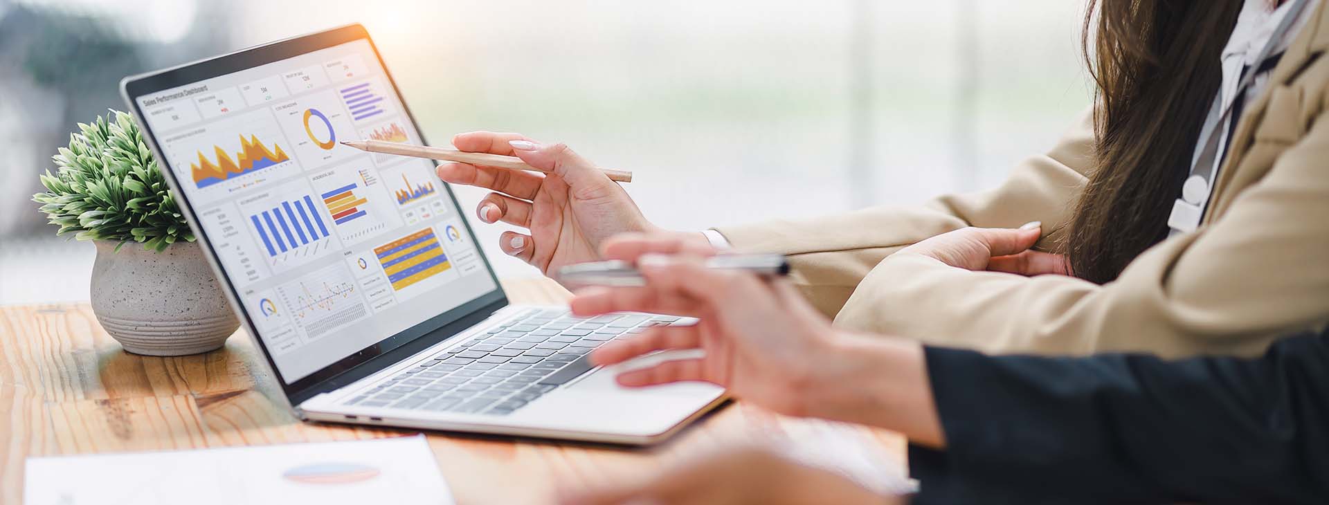 Two professionals analyzing data graphs on a laptop 