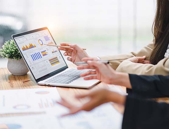 Two professionals analyzing data graphs on a laptop 