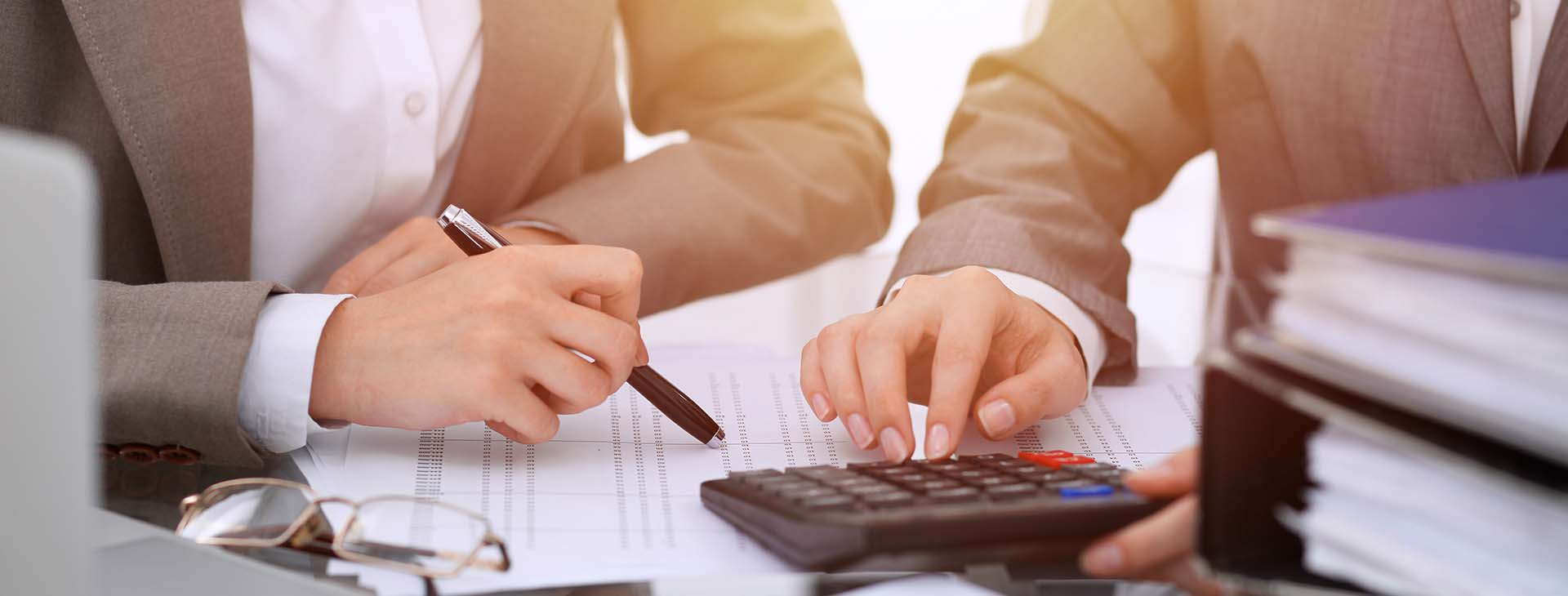 Two female accountants counting on calculator 
