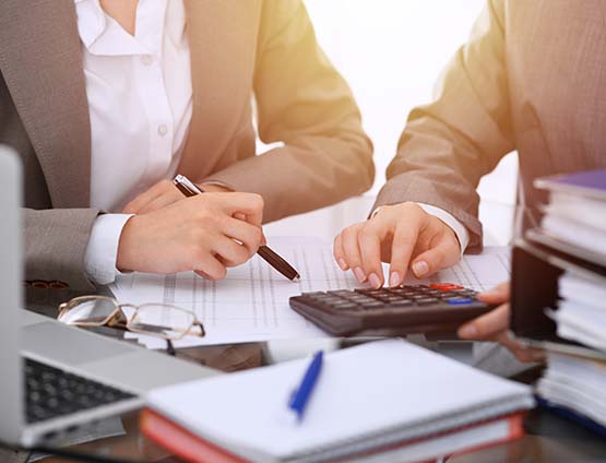 Two female accountants counting on calculator 
