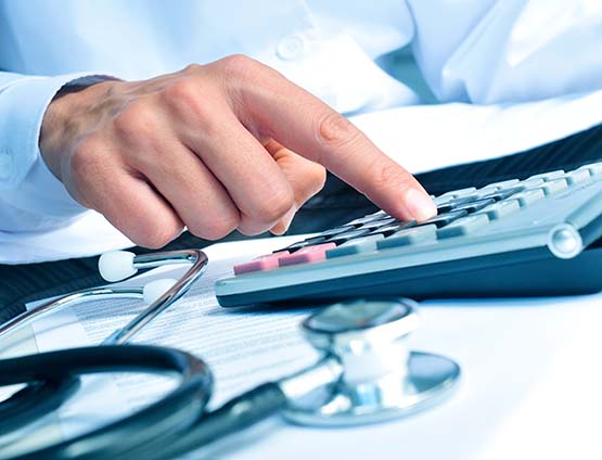 Image of man using calculator next to a stethoscope 