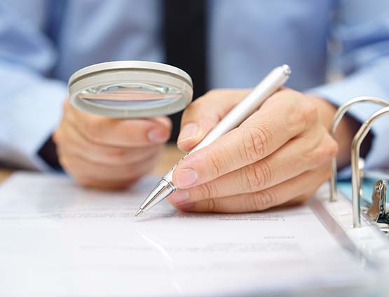 Man reviewing a financial report with magnifying glass