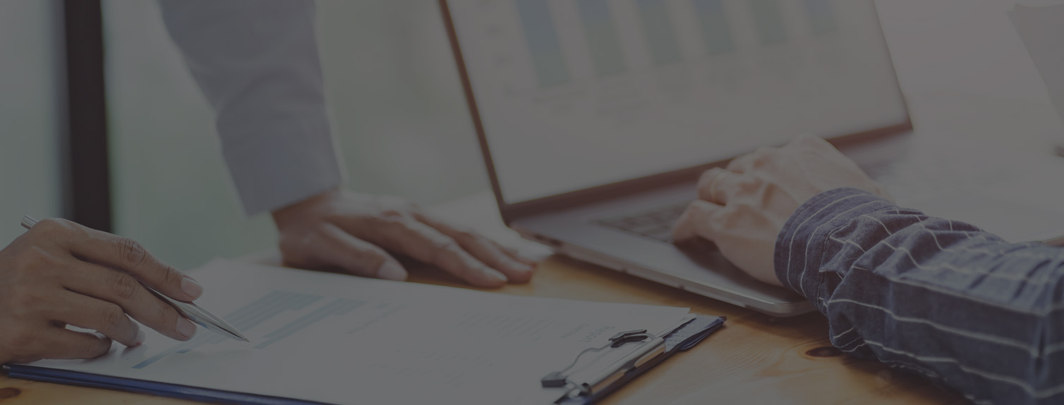 two pairs of hands reviewing financial documents with graphs