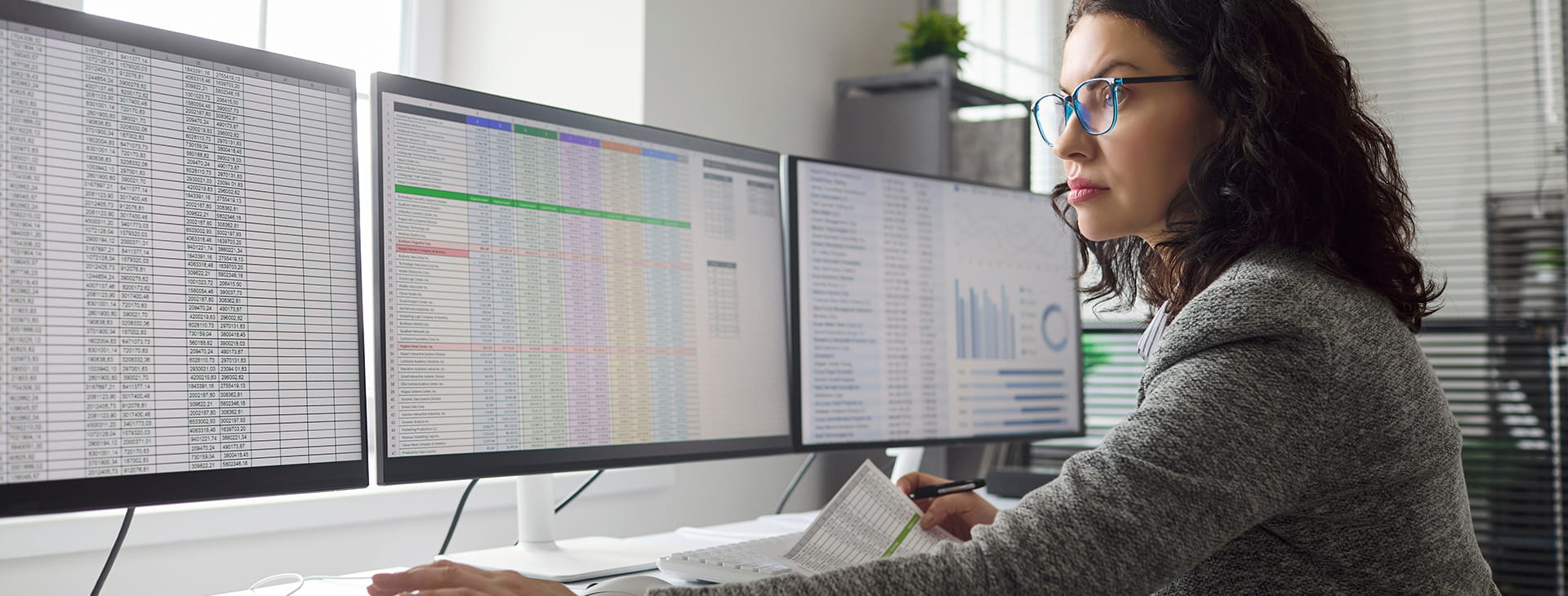 woman staring at 3 computer screens of data