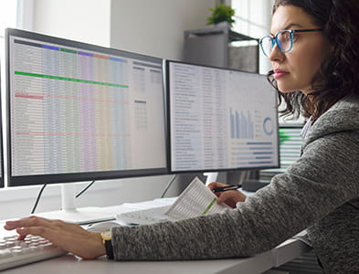 woman staring at 3 computer screens of data