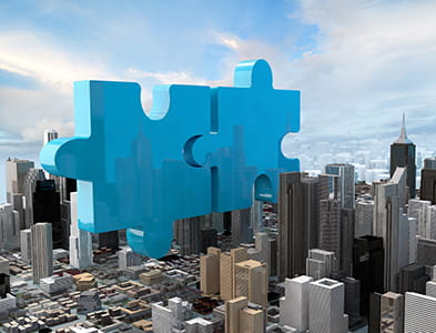 puzzle piece with office buildings to create a concept of a merger and acquisition