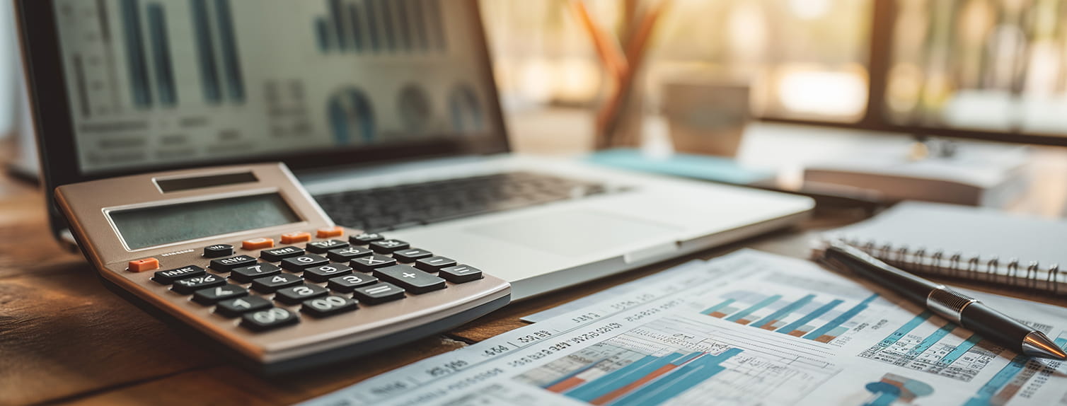 An office desk of an accountant with calculator, laptop and financial documents and charts