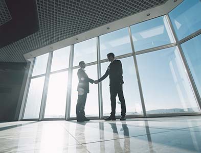 Image of two men shaking hands with large window in the background