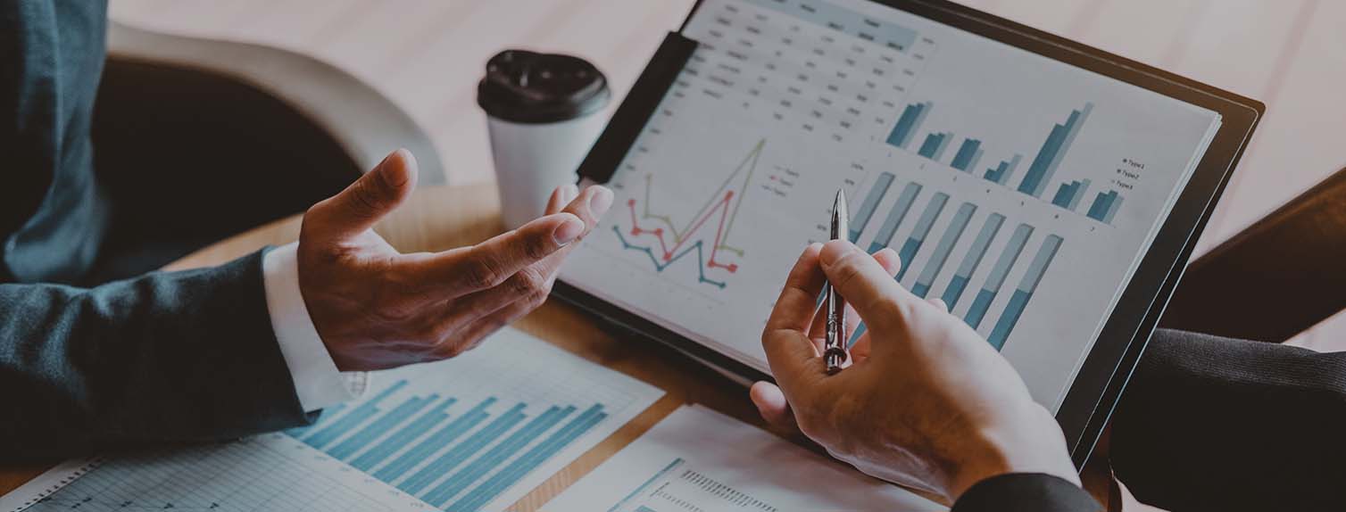 two pairs of hands reviewing financial documents with graphs